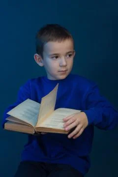 Studio portrait of boy on blue background in a classic t-shirt. Holding a boo Stock Photos