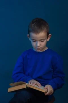 Studio portrait of boy on a blue background in a classic t-shirt. With a book Stock Photos