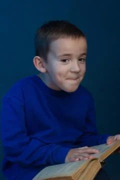 Studio portrait of boy on a blue background in a classic t-shirt. With a book Stock Photos