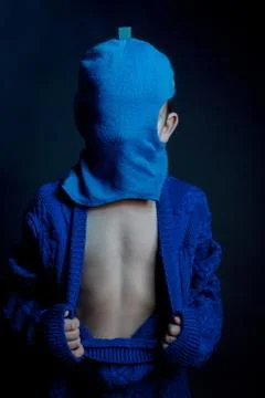 Studio portrait of boy in a blue unbuttoned knitted jacket, blue Balaclava, t Stock Photos