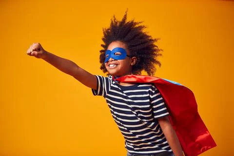 Studio Portrait Of Boy Dressed As Comic Book Superhero Against Yellow Background Stock Photos
