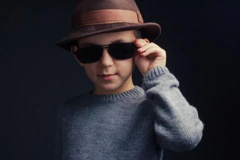 Studio portrait of a boy in a grey sweater, brown hat and sunglasses Stock Photos