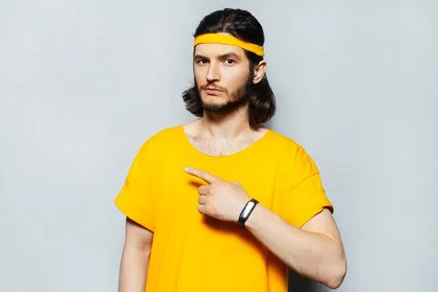 Studio portrait of confident guy pointing with finger away on grey background. Stock Photos