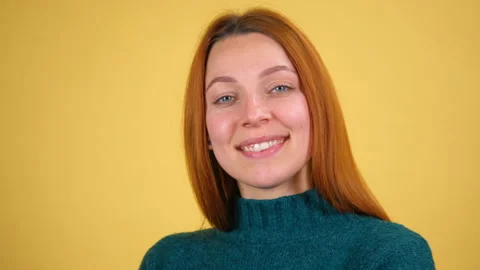 Studio portrait of confident smiling young woman laughing against yellow Stock Footage 148585245