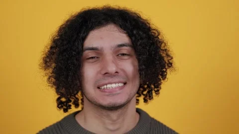 Studio portrait of confident smiling young man laughing against yellow Stock Footage 260681064