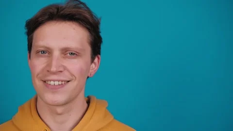 Studio portrait of confident smiling young man laughing against blue background Stock Footage 263884984