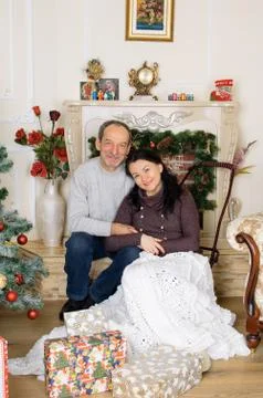 Studio Portrait of Couple with Age Difference Sitting near Artificial Fireplace Stock Photos
