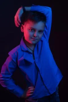 Studio portrait of a dark-haired boy, on a dark background, in a hoodie jacke Stock Photos