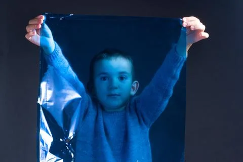 Studio portrait of a dark-haired boy in a knitted sweater, holding a polyethy Stock Photos