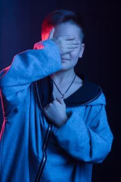 Studio portrait of a dark-haired boy, on a dark background, in a hoodie jacke Foto stock