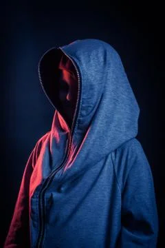 Studio portrait of a dark-haired boy, on a dark background, in a hoodie jacke Stock Photos