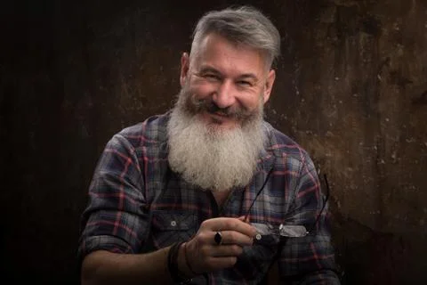 Studio portrait of a gray-haired middle-aged bearded man smiles at the camera Stock Photos
