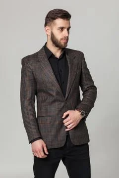 Studio portrait of handsome elegant young man in brown jacket posing. Stock Photos