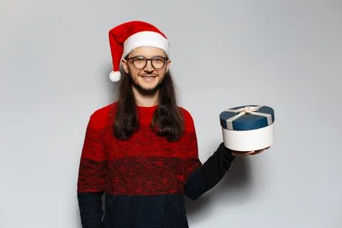 Studio portrait of handsome smiling guy. Holding gift box in hand. Wearing .. Stock Photos
