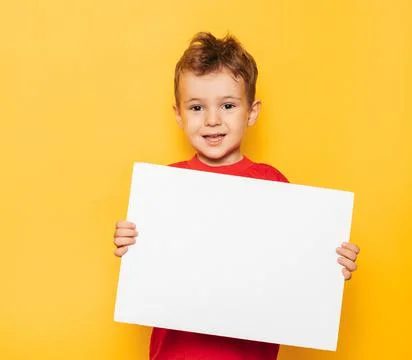 Studio portrait of a happy boy with a clean white poster in his hands on a Stock Photos