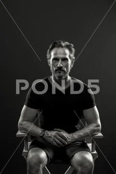 Studio portrait of mid aged man sitting on chair. Stock Photos