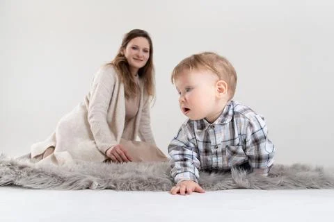 Studio portrait of a one-year-old baby crawling on the carpet and being watched Stock Photos