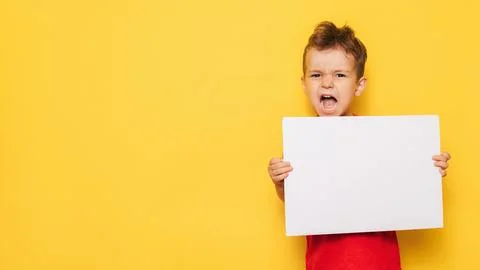 Studio portrait of a screaming boy with a clean white poster in his hands on a Stock Photos