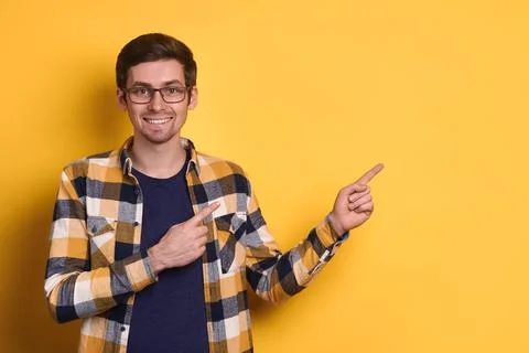 Studio portrait of smiling guy pointing with index fingers at free space on Foto stock