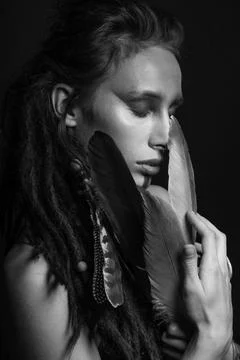 Studio portrait of woman with make-up, dreadlocks and bird feathers Foto stock