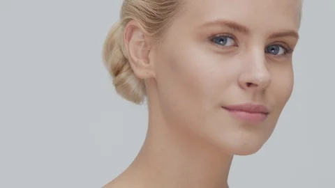 Studio portrait of young, beautiful and natural blond woman applying skin care Stock Footage 117698904