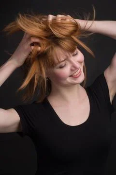 Studio portrait of a young brown-haired woman, on a black background Stock Photos