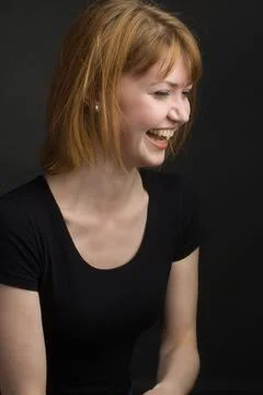 Studio portrait of a young brown-haired woman, on a black background Stock Photos