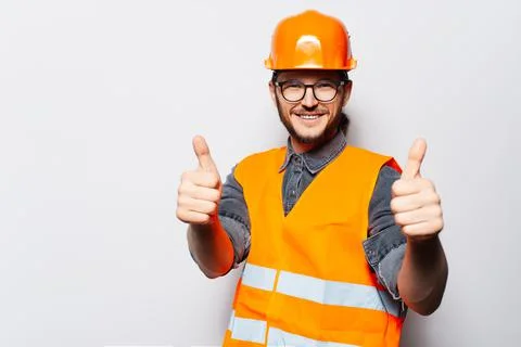 Studio portrait of young construction worker on white, showing thumbs up. Stock Photos