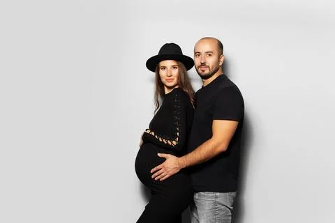 Studio portrait of young couple, future parents. Husband hugging a his wife.. Stock Photos