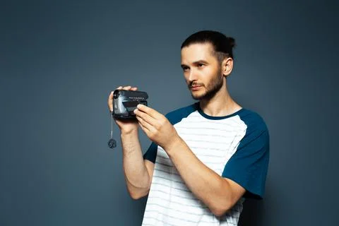 Studio portrait of young guy with digital video camera in hands. Stock Photos