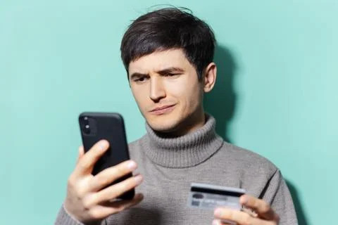 Studio portrait of young guy using smartphones and credit card. Stock Photos