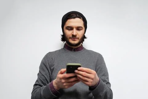 Studio portrait of young man using smartphone on white background. Stock Photos