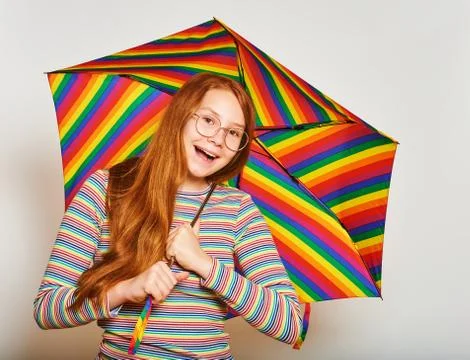 Studio portrait of young red-haired girl holding colorful umbrella Stock Photos