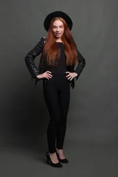 Studio portrait of a young red-haired woman in black clothes on a black backg Stock Photos