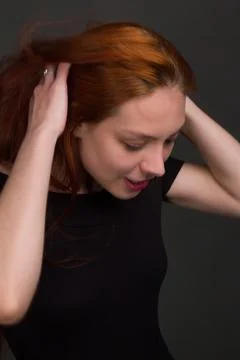 Studio portrait of a young red-haired woman in black clothes Stock Photos