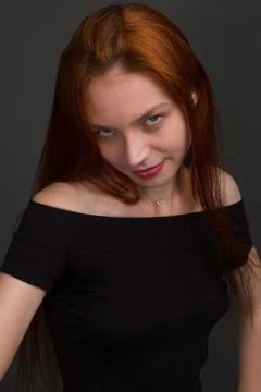 Studio portrait of a young red-haired woman in black clothes 스톡 사진