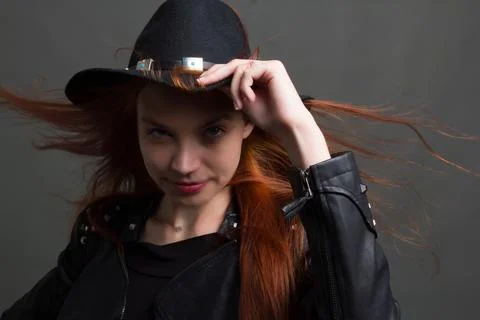 Studio portrait of a young red-haired woman in black clothes on a black backg Stock Photos