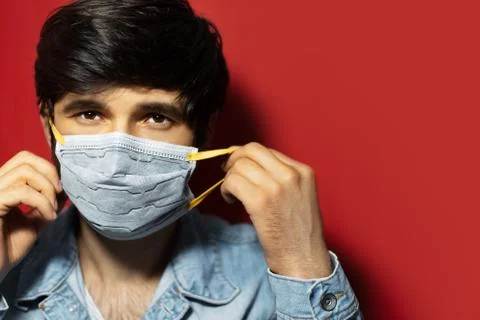 Studio portrait of young sick guy in denim jacket, put on medical face mask. Stock Photos