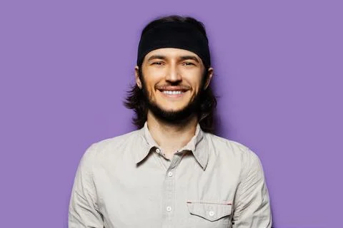 Studio portrait of young smiling man, with long dark hair and cheerful. Stock Photos