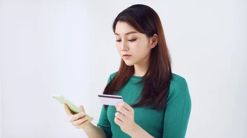 Studio shoot of attractive smiling young woman holding credit card and mobile Stock Footage 125069406
