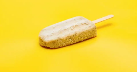 Studio shoot of green bean popsicle melting time lapse on yellow background Stock Footage 94239011