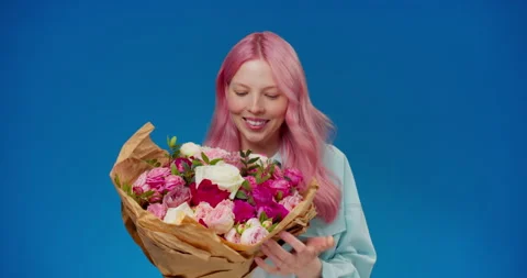 Studio shoot of happy and surprised young woman with pink hair holding bouquet Stock Footage 153385481