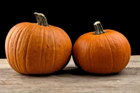 Studio shot of beaded orange pumpkins on wooden plank isolated on black backg Stock Photos