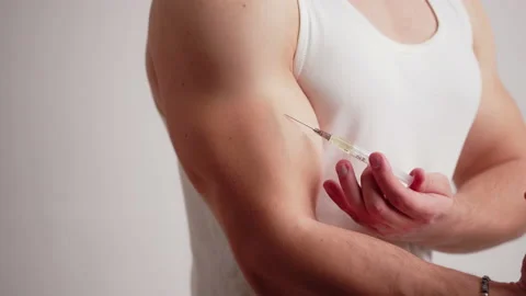 Studio shot of bodybuilding cheater using doping by injection to his biceps Stock Footage 176562470