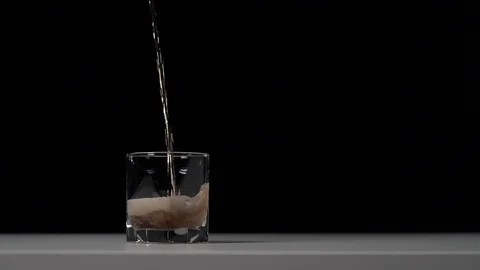 Studio shot of Cola pouring into transparent glass on white table. Stock Footage 126319597