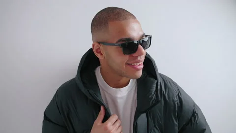 Studio shot of confident street style loving man in sunglasses, putting on his Stock Footage 237453553