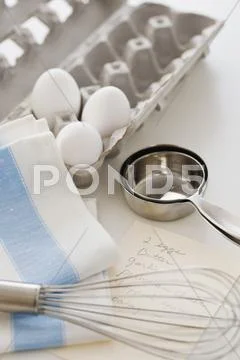 Studio shot of eggs, egg whisk and recipe Stock Photos