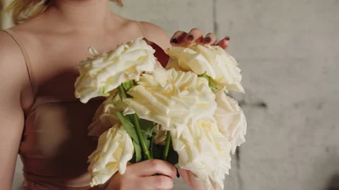 Studio shot of fairhaired bride touching cream petals with graceful ensemble Video stock 331880085