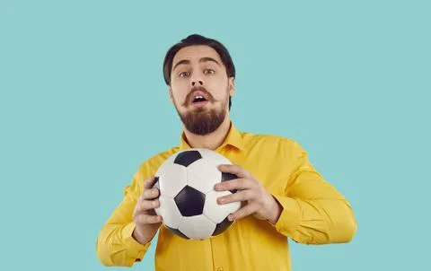 Studio shot of funny shy guy in shirt holding soccer ball with scared face Stock Photos