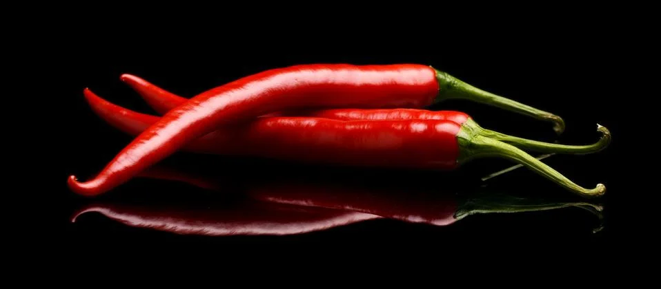 Studio shot of group of red chilli peppers isolated on a black background Stock Photos